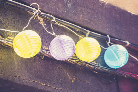 Row of colorful small lanterns hanging on rough wall. の写真素材