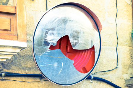 Broken round mirror glass on street wall reflecting bright light. の写真素材