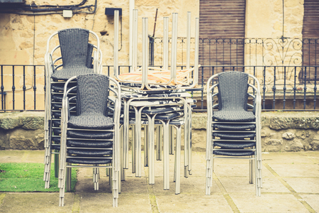 View of stacked garden chairs and tables in backyard.の写真素材