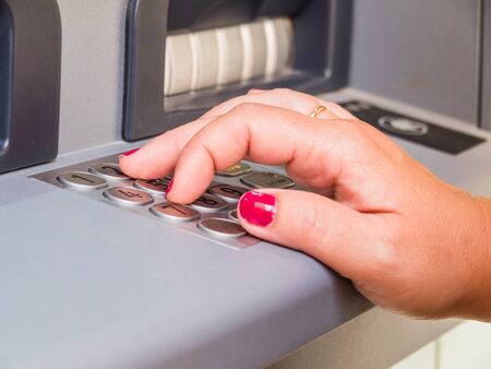 Close-up of woman's hand pushing button on atm.の写真素材