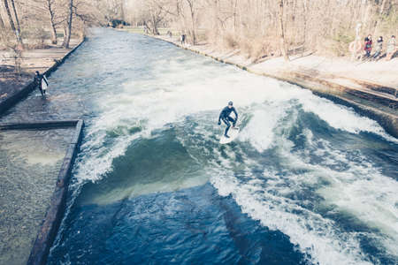 MUNICH, GERMANY - 14 MARCH 2016: Unrecognizable person surfing on artificial waves in Englischer Gartenのeditorial素材
