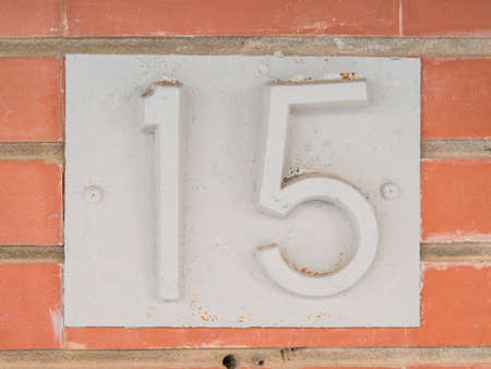 The fifteen house number placed on the brick wall.の写真素材