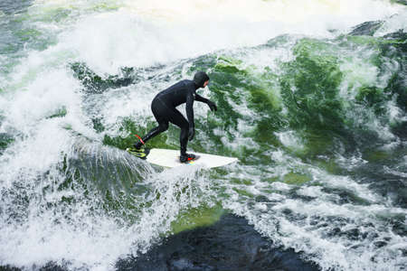 MUNICH, GERMANY - 14 MARCH 2016: Unrecognizable person surfing on artificial waves in Englischer Gartenのeditorial素材