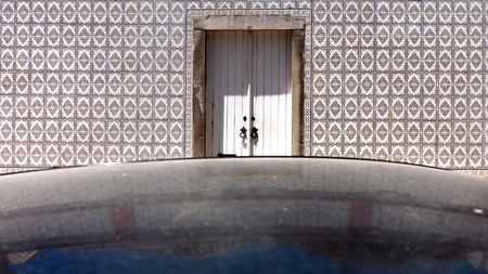 Door and tiled wall of an old Portuguese house with reflection of car roofの写真素材