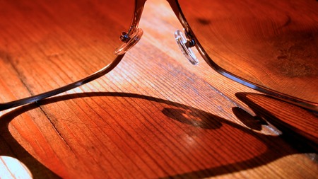 Close up sunglasses on the wooden surface with shadow under sunlightの写真素材