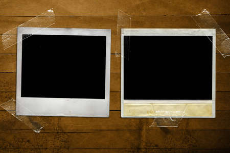A Pair of old polaroids taped to a grunge wood textured background. Add your own photo or message.の写真素材