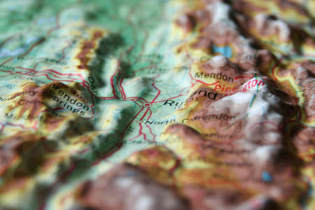 A macro photo of Topographic Map relief map with a focus on a valley town surrounded by mountainsの写真素材