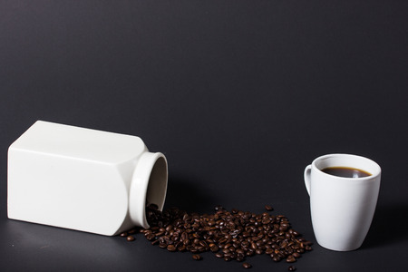 Coffee beans pouring from a white jar and a fresh made americano coffeeの写真素材