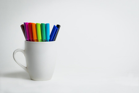 A group of color markers in a white cup on an isolated backgroundの写真素材
