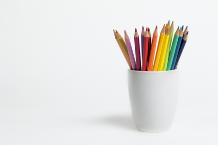 Multi colored pencils forming a rainbo in a white cup on an isolated backgroundの写真素材