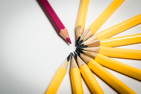A red pencils standing out from a group of yellow pencilsの写真素材