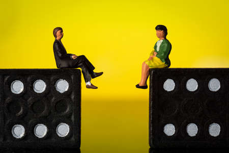 Business man and Woman Sitting on domino tokens Yellow background