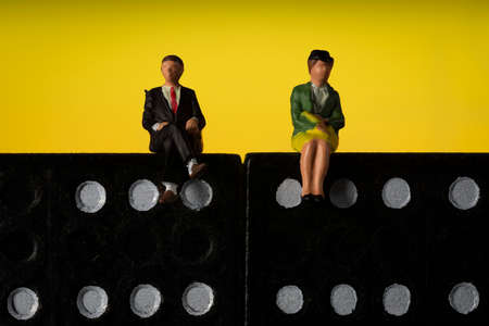 Business man and Woman Sitting on domino tokens Yellow background