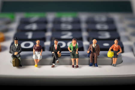Miniature people: Seniors sitting at a calculator. social security income and pensions. Saving money...