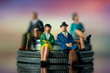 Miniature people sitting on stack of coins. Concept of financial planning for retirementの写真素材