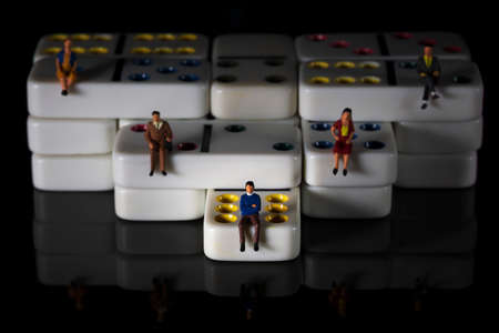 miniature people on white colored dominoes Black backgroundの写真素材