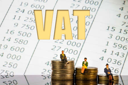 Miniature people: people sitting on coins stack. VAT text accounting backgroundの写真素材