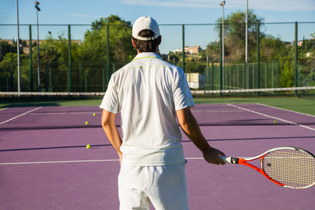 Professional tennis player playing the game on the tennis court. He Has His back to the camera and Have the racket in His right hand. I is in the center of the image.の写真素材