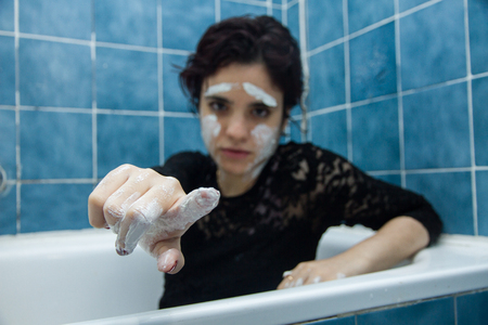 Girl with white face paint With short hair and brown eyes bathing in a bathtub full of water and milk. She is enjoying bathing in hot water. She is playing and enjoying painting.の写真素材