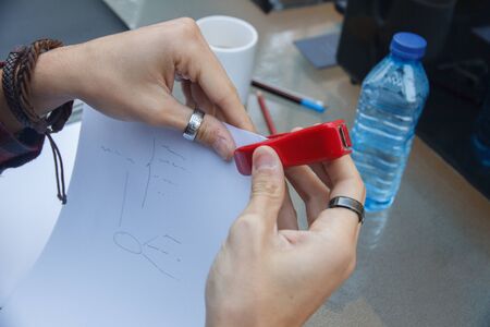 Closeup photo of a person with a stapler stapling documents on a table.