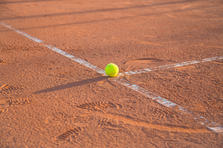 Tennis ball lying on white line on tennis court on sunny day.の写真素材