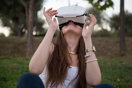 Smiling brunette having fun while using glasses of virtual reality in park.
