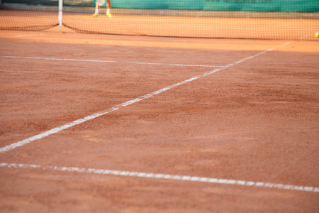 Ground on tennis court with white lines in daylight.