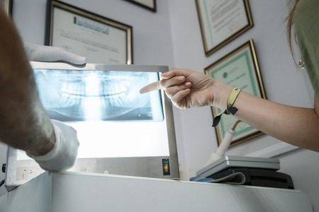 Young woman looking at the x-ray of her mouth while the dentist explains to her at the dental...
