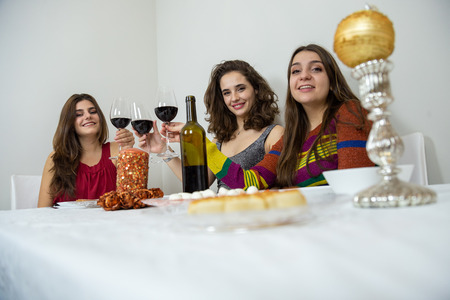Brunette women having Christmas celebration clinking with wineglasses and smiling at cameraの写真素材