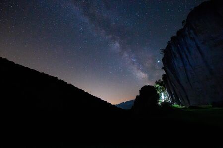 Picturesque view of shining stars and Milky Way on dark summer sky in mountainsの写真素材