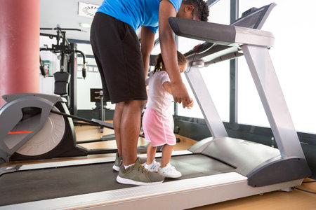 Crop dad exercising with daughter on treadmillの写真素材