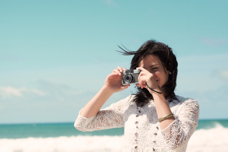 Beautiful young girl taking photos on the beachの写真素材
