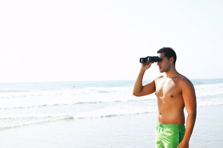 portrait of a  handsome boy with binoculars  looking at the seashoreの写真素材