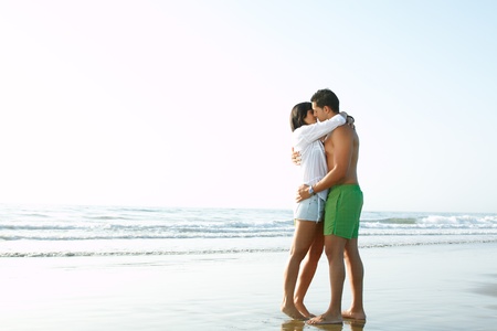 portrait of an adorable  couple in love kissing and embracing each other on the edge of the beachの写真素材
