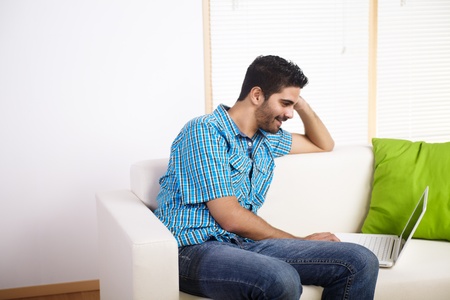 Young man using a laptop on a couch.の写真素材