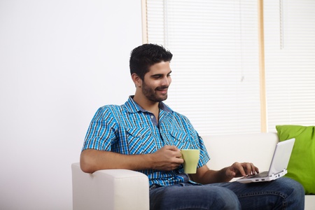 Young man drinking coffee and using laptop.の写真素材