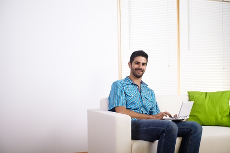 Young man using a laptop on a couch.の写真素材