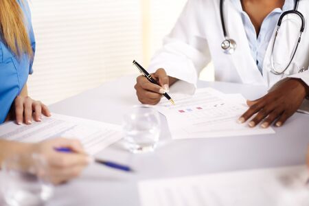 Portrait of a doctor talking on a meeting with two of his co-workersの写真素材