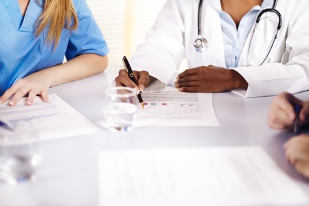 Portrait of a doctor talking on a meeting with two of his co-workersの写真素材