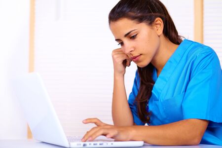 Portrait of a cute young nurse using a laptop.の写真素材