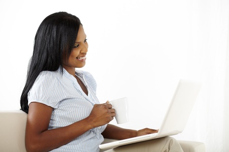 Natural portrait of a cute young woman working on laptop at homeの写真素材