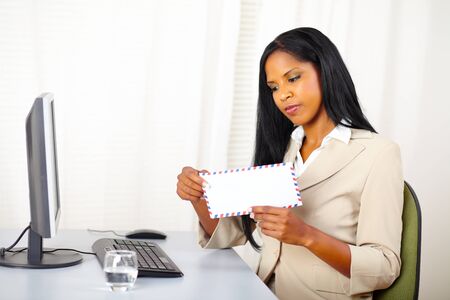 Portrait of a beautiful young executive woman at work while open a letterの写真素材