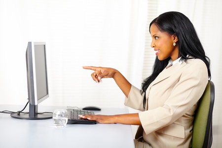 Portrait of a beautiful young businesswoman surprised while pointing the monitor screenの写真素材