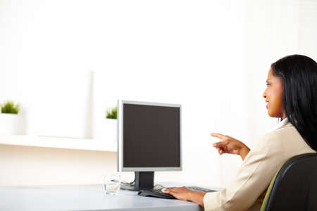 Portrait of a cheerful businesswoman looking  and pointing to the monitor screen with copy space.の写真素材