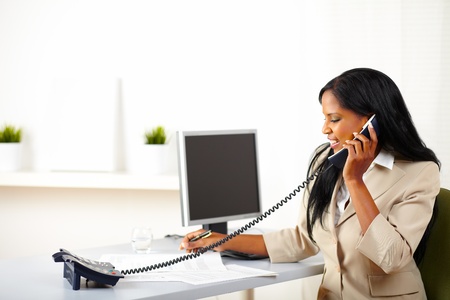 Portrait of a young professional woman conversing on phone while working with documentsの写真素材
