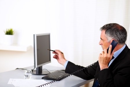 Portrait of a elegant businessman pointing the computer screen at the officeの写真素材