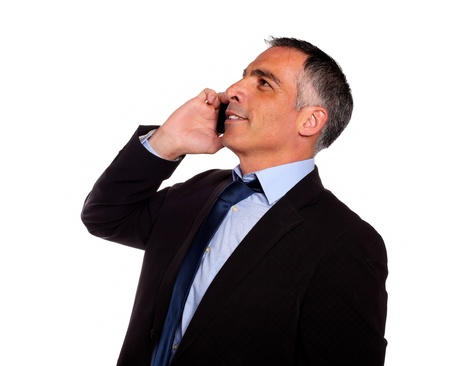 Portrait of a hispanic professional man conversing on mobile and looking up against white backgroundの写真素材