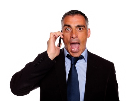 Portrait of a surprised business man on cellphone against white backgroundの写真素材