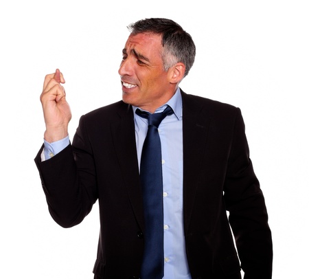 Portrait of a hispanic senior businessman praying for luck on black suit against white backgroundの写真素材