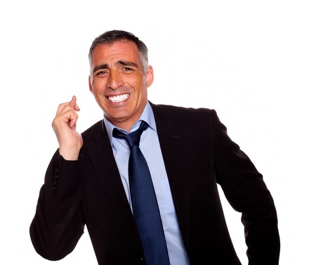 Portrait of a friendly hispanic businessman crossing the fingers against white backgroundの写真素材